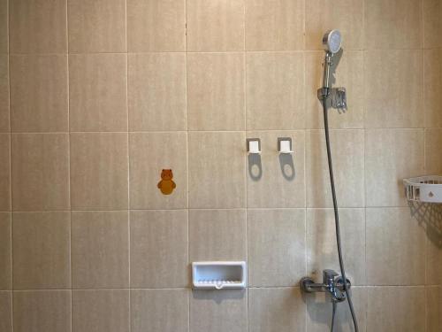 a shower in a bathroom with a tile wall at Family Only Cozy Villa on Top of Bandung - De Reiz Iris Syariah 4BR in Ciburial