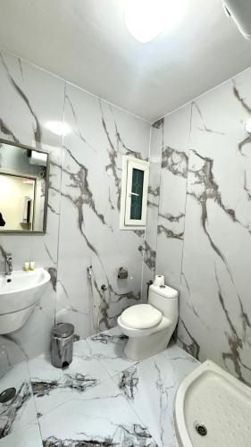 a white bathroom with a toilet and a sink at Collection O Muscat Airport Hotel Apartments in Ghursheba