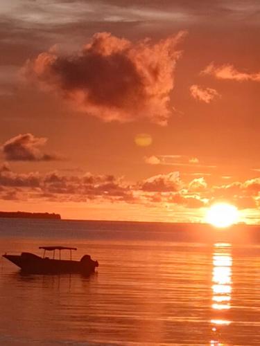 a boat sitting on the water at sunset at Tria Maria Cottage in Ngurblut