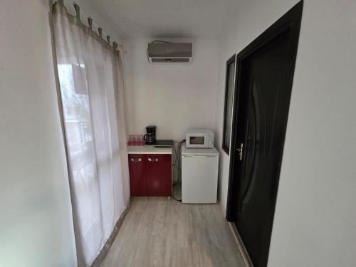 a hallway with a small kitchen with a refrigerator and a window at Alex Residence in Otopeni