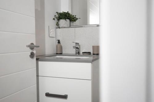a white bathroom with a sink and a mirror at Bridgewater Studio Century City in Century City