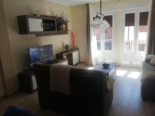 Una sala de estar con un sofá y un televisor. en El piso de Amalia, en Casalarreina