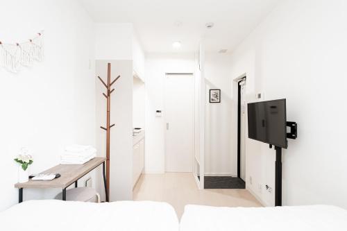 a white living room with a tv and a table at テルヌファビュル亀戸 - Tokyo Urban APT in a Japanese Local Shopping Street, with Direct Access to Shinjuku & Akihabara in Tokyo