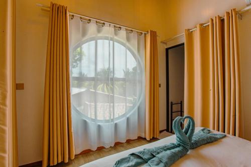 a bedroom with a large window with yellow curtains at Sunny Stay Dhigurah in Dhigurah