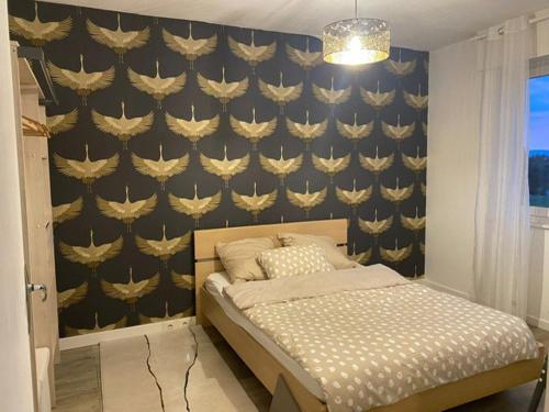 - une chambre avec un lit et un mur orné d'aavid dans l'établissement Élégance et classe sur axe majeur Metz T2, à Metz
