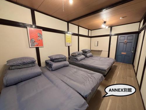 a room with three beds in it at 777 Takamatsu Guest House in Takamatsu