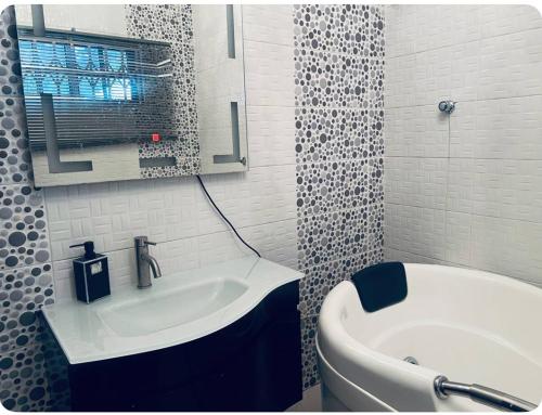 a bathroom with a sink and a tub and a mirror at The Peacock Mansion in Kumasi