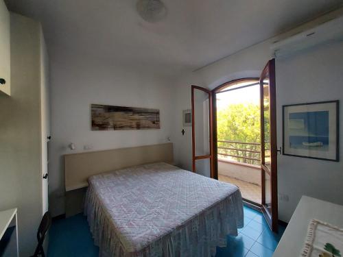 a bedroom with a bed and a door to a balcony at Villetta Elena Via Loreto 64 villa 14 in Marcelli