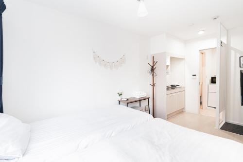 a white bedroom with a large white bed and a bathroom at テルヌファビュル亀戸 - Tokyo Urban APT in a Japanese Local Shopping Street, with Direct Access to Shinjuku & Akihabara in Tokyo
