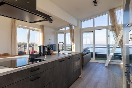a kitchen with large windows and a view of the water at Vakantiewoning aan het water - met dakterras en balkon - Vista Maris - Nr 48 in Sint Annaland