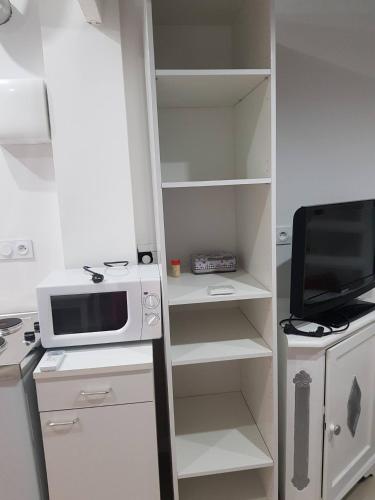 a white kitchen with a microwave and a tv at Bas de maison envoutant in Saint-Louis-du-Rhône
