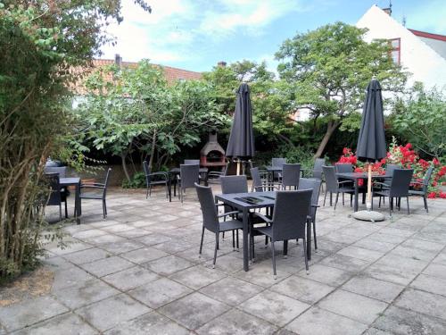 a group of tables and chairs with umbrellas on a patio at Apartment by the beach - Great facilities and consumption included in Allinge