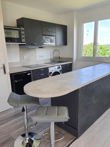 une cuisine avec un comptoir, une table et des chaises dans l'établissement Grand T2 tout confort au calme avec terrasse, à Lagarrigue