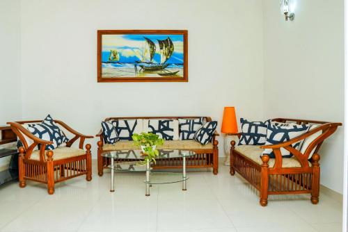 three chairs and a table with a picture on the wall at Rosemary Villa - Welegoda, Matara in Matara