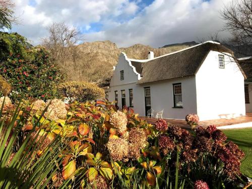 a white house with flowers in front of it at Keerweder Cottages in Franschhoek