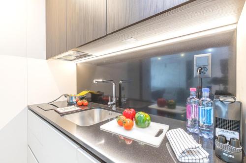 a kitchen counter with a sink and vegetables on a cutting board at ICON H Lugano - Luxury Suites & Apartments in Lugano