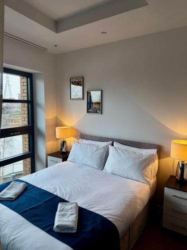 a bedroom with a large white bed with two lamps at London City Island 1 Bedroom Luxury Apartments, Private Balcony in London
