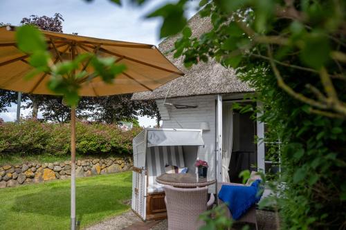 a table and chairs under an umbrella next to a shed at Benen-Diken-Hof in Keitum