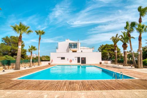 a villa with a swimming pool and palm trees at PRECIOSO DUPLEX EN CALA SANTANDRIA CON PISCINA Y WIFI in Son Carrio