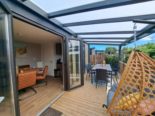 a patio with a hammock on a deck at Luxe Chalet met Veranda en Tuin , nabij Zwembad VP006 in Heinkensand