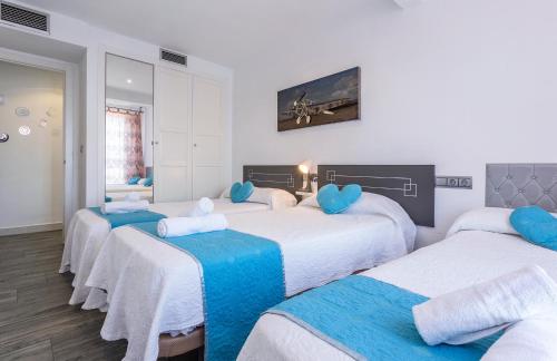 a room with four beds with blue pillows at Apartments Vistas Mar Bahia in Cádiz
