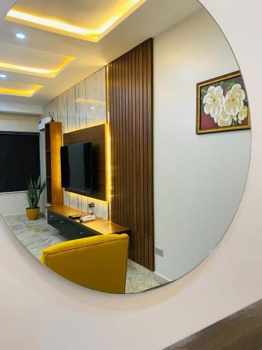 a mirror reflecting a room with a tv and a yellow chair at Calini Apartment in Mobushipe