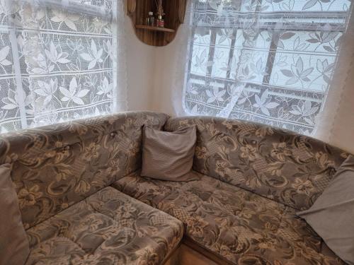 a brown couch sitting in front of a window at Mobil-Home N 17 in Fourmies