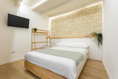 a bedroom with a bed and a stone wall at Loft La Torre in Cagliari