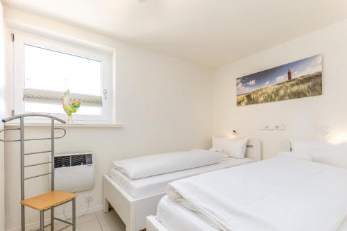 een witte slaapkamer met twee bedden en een raam bij Appartement Luk in Westerland