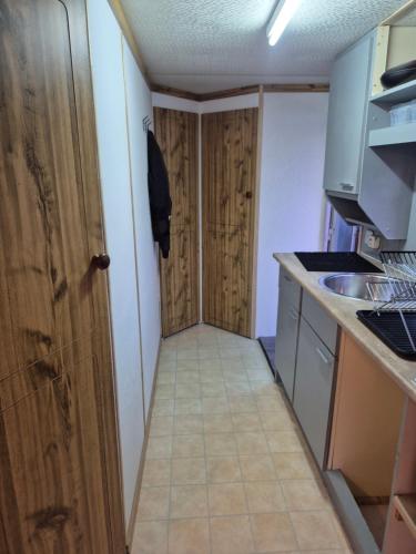 a small kitchen with a door and a sink at Mobil-Home N 17 in Fourmies