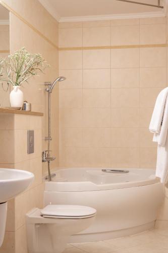 a bathroom with a tub and a toilet and a sink at Czarny Potok Wellness & Spa Zakopane Centrum in Zakopane