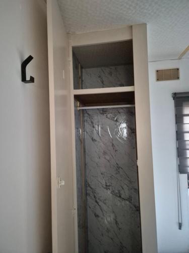 a glass door in a room with a marble wall at Mobil-Home N 17 in Fourmies