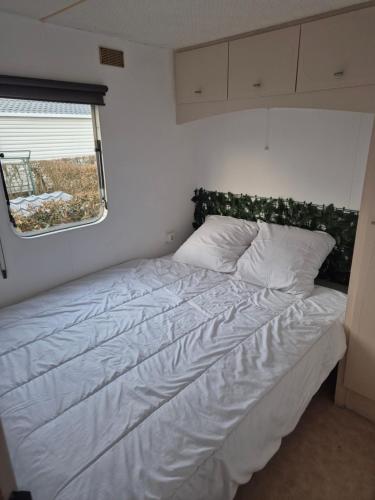 a bed in a small bedroom with a window at Mobil-Home N 17 in Fourmies