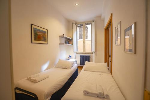 two beds in a small room with a window at Cozy 2BR Apartment near Piazza Navona in Rome