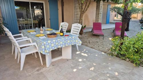 une table avec des chaises blanches et un chiffon de table bleu et blanc dans l'établissement Maison provençale rénovée, à Pernes-les-Fontaines