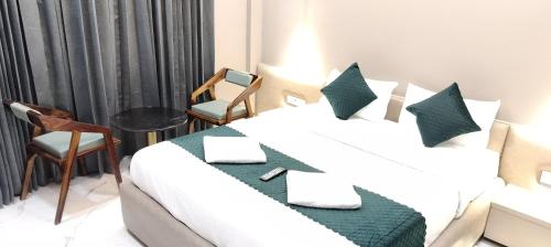 a hotel room with a bed and two chairs at Hotel Laxmi Elite Karad in Karad