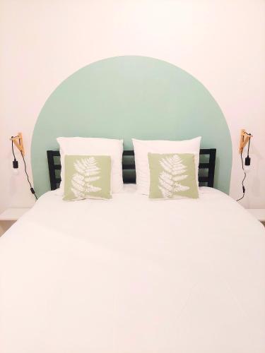 un lit blanc avec deux oreillers dessus dans l'établissement Cosy 1 - Audincourt centre, à Audincourt