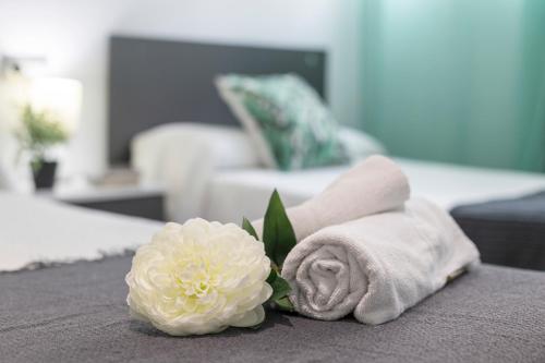 a pile of towels and flowers on a bed at Apartments Vistas Mar Bahia in Cádiz