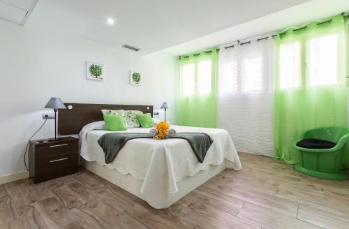 a bedroom with green curtains and a bed with a table at Apartments Vistas Mar Bahia in Cádiz
