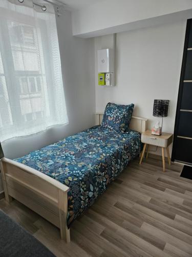 une chambre avec un lit avec un couvre-lit bleu dans l'établissement Studio cosy à 5min à pieds de la gare, à Valenciennes