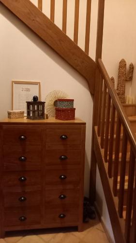une commode en bois à côté d'un escalier dans l'établissement Chambre Bleue, lit double 2 personnes, Maison en plein coeur du Parc Régional du Vexin, à Hérouville