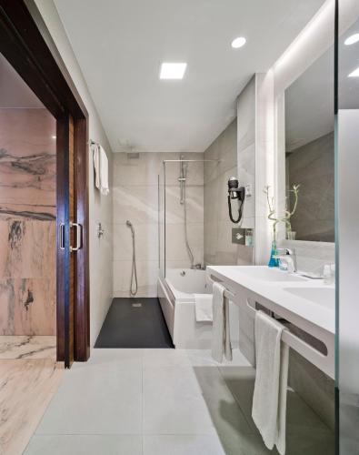 a bathroom with two sinks and a tub and a shower at Hotel Murcia Rincón de Pepe Affiliated by Meliá in Murcia