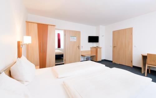 une chambre d'hôtel avec un grand lit et un bureau dans l'établissement Tagungszentrum Neuendettelsau, à Neuendettelsau