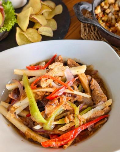 a white bowl of food with vegetables on a table at Kayong's Inn in Dumaguete