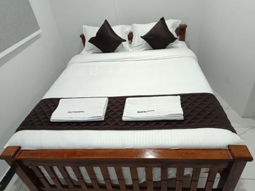 a bed with white sheets and black and white pillows at Royal Residency in Chennai