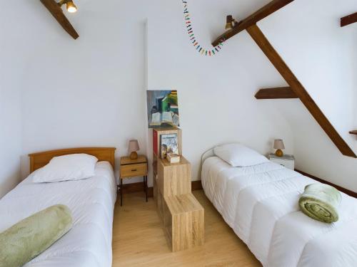 Ce lit se trouve dans un dortoir doté de murs blancs et de poutres apparentes. dans l'établissement Charmante maison avec jardin pour 4, Penmarch, à Penmarcʼh