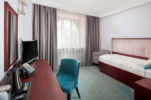 a hotel room with a bed and a desk and a television at Hotel Kultúra in Ružomberok