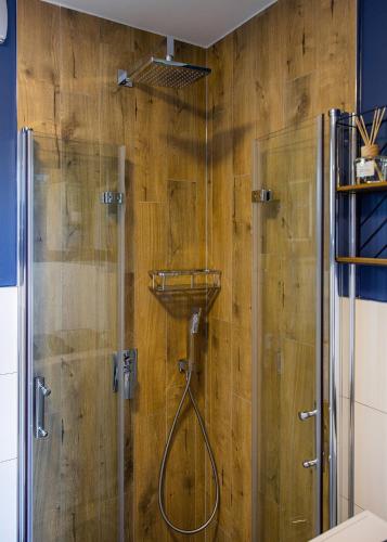 a shower in a bathroom with a wooden wall at Forrest Houses Bartosze in Bartosze