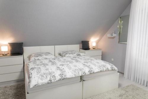 a white bedroom with a white bed and two night stands at Apartment Wallberg "Nest" in Detmold