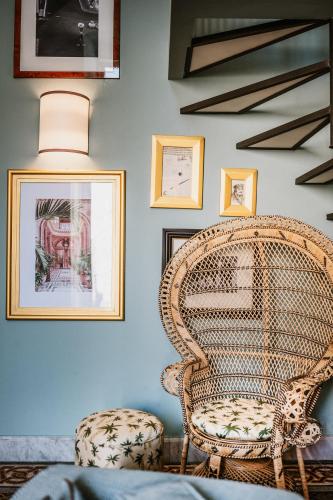 a wicker chair in a room with pictures on the wall at Palazzo Flora in Gallipoli